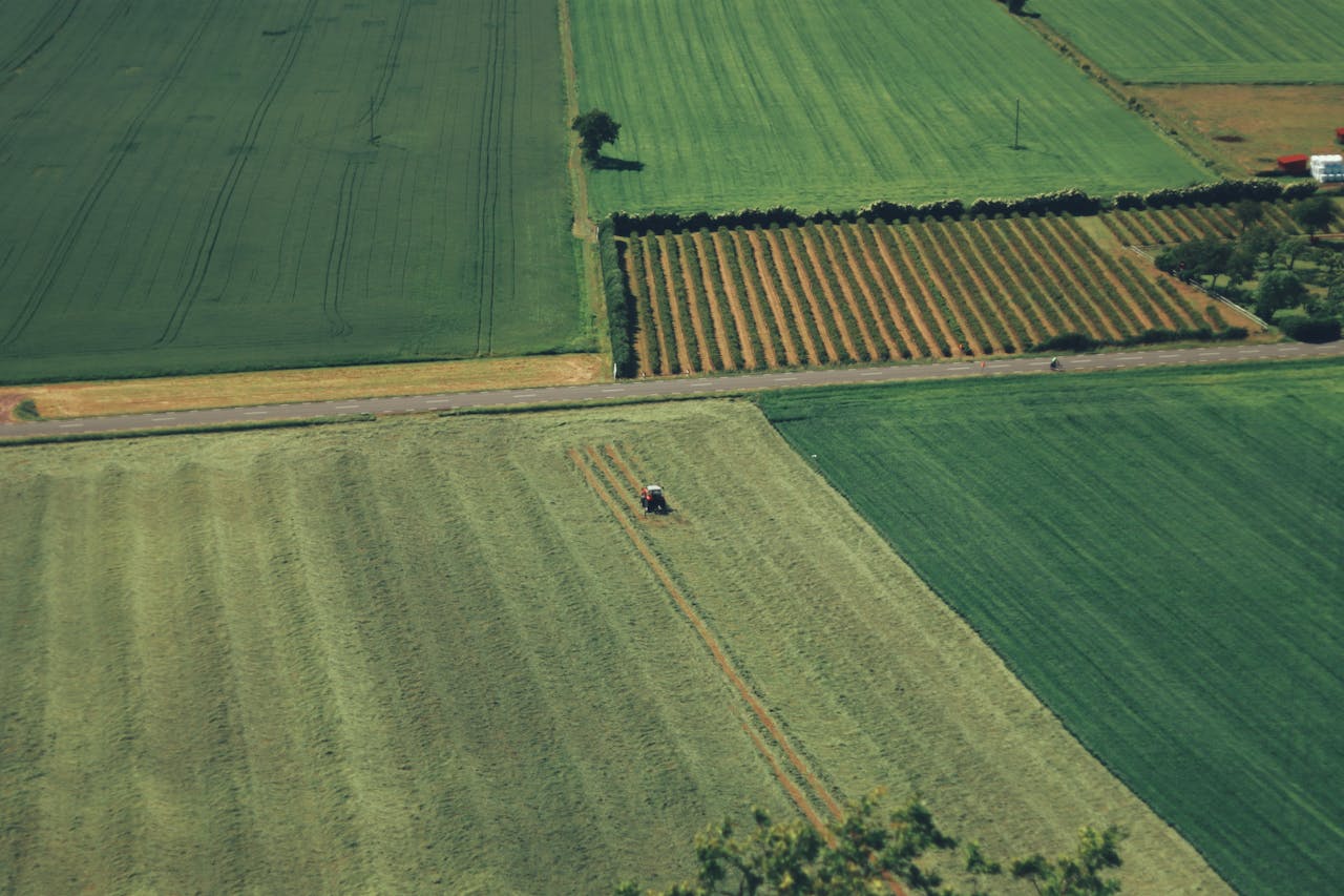 Aerial view of lush green farmlands with tractor in Jönköping, Sweden, during summer.