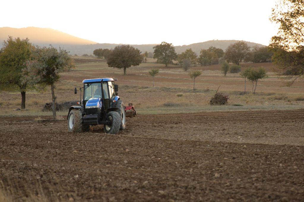 A tractor cultivating farmland at sunset in a rural landscape. Perfect for agricultural themes.